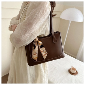 Sac fourre-tout en cuir marron avec foulard en soie orange et éclairage intérieur doux