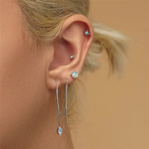 Macro view of S925 silver opal earrings and star stud set worn on earlobe