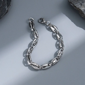 Detail of silver stainless steel chain bracelet with lobster clasp on dark stone blocks