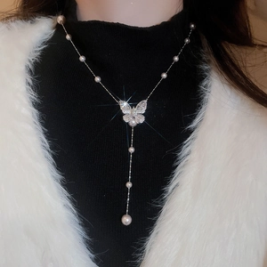 Dettaglio della collana di perle a farfalla con strass scintillanti su modella