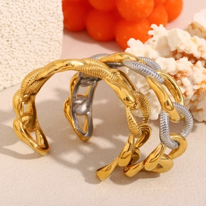 Ensemble de joncs à grosse chaîne plaqués or 18 carats sur sable beige et pierres corail