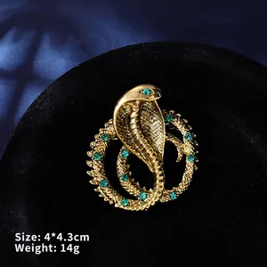 Macro shot of a golden cobra snake brooch with green crystals measuring 4.0 by 4.3 cm