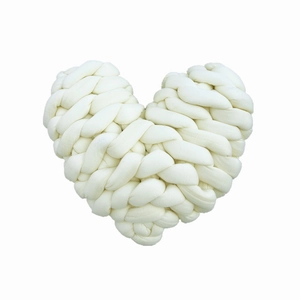 Detailed view of hand-knitted white heart pillow with thick cotton yarn texture