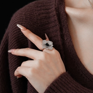 Macro shot of a silver flower ring featuring a black gemstone and small white crystals