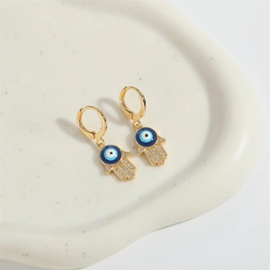 Goldene Hamsa-Ohrringe mit blauem Evil Eye Emaille und Zirkon auf Keramikschale