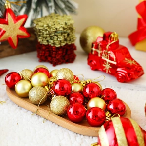Close-up of red and gold Christmas ball ornaments with mixed textures in a wooden tray