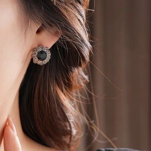 Macro shot of vintage floral earring with black gemstone and sparkling crystals on ear