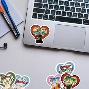 Close-up of retro heart-shaped stickers featuring cute pets on a laptop keyboard