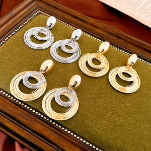 Macro shot of coiled geometric hoop earrings in gold and silver finish on velvet display