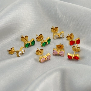Elegant bow stud earrings in four colors on silver silk background, minimalist style