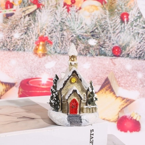 Detail of miniature snow-covered resin house with red door and festive Christmas trees