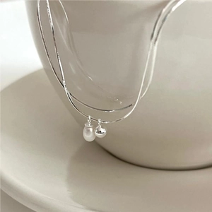 Macro detail of S925 silver snake chain with pearl and polished bead on ceramic cup