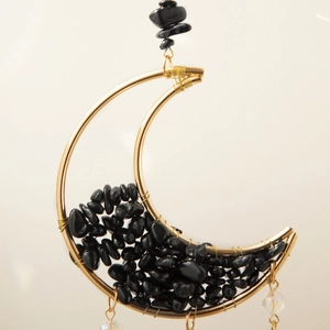 Detail of moon-shaped gold wire frame with black natural stone chips and clear beads