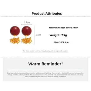 Detail view of 18k gold-plated dark red resin stud earrings with zircon and silver pins