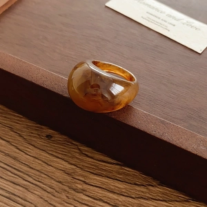 Vue détaillée d'une bague ovale en résine ambrée sur un plateau en bois rustique chic