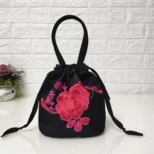 Detail of red peony embroidery on black satin drawstring bucket bag with handle