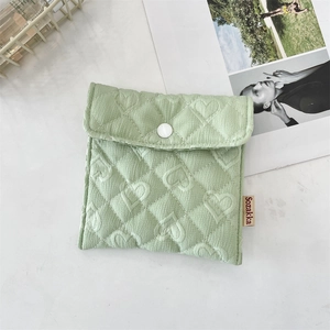 Dettaglio del tessuto trapuntato verde chiaro con motivi a cuore sulla piccola borsa portaoggetti