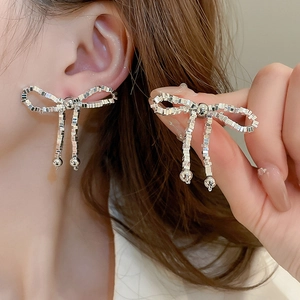 Détail des boucles d'oreilles nœud argenté avec perles fines et effet de franges