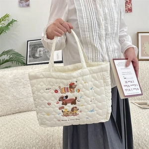 Close-up of quilted heart pattern and cute dog embroidery on a cream tote bag