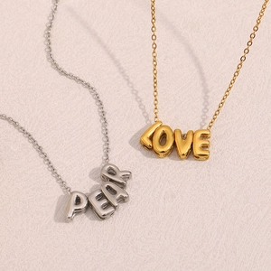 Gros plan de colliers en acier inoxydable doré et argenté avec pendentifs LOVE et PEAR