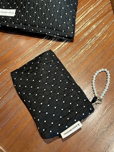 Detail of black polka dot quilted makeup bag with elegant pearl carry handle