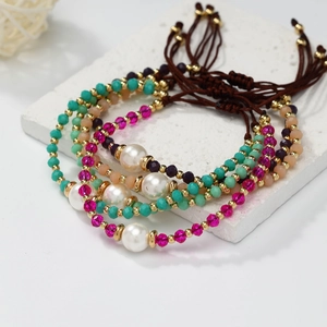 Detail of four colorful beaded friendship bracelets with pearls on a white stone pedestal