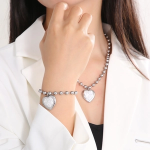 Silver bead necklace and bracelet set with textured heart pendants worn by a model