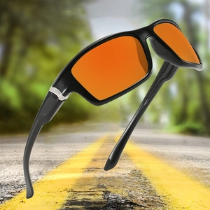 Close-up of cycling sunglasses with orange lenses and black frames on road background