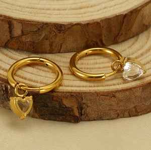 Detailed macro view of heart zircon pendant on golden titanium steel hoop earrings