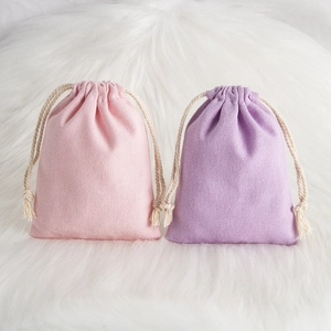 Detailed texture of pink and purple cotton drawstring jewelry pouches on white faux fur