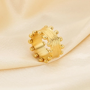 Dettaglio anello in oro 18K con perline e texture spazzolata su tessuto in seta beige