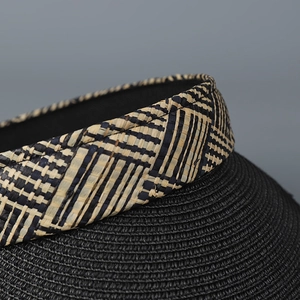 Détail du bord d'un chapeau de paille tissé avec liseré à carreaux noir et beige