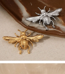 Detailed macro of bee-shaped brooches in gold and silver finish on textured ceramic