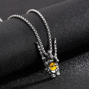 Detail of silver dragon claw pendant with yellow tiger eye stone on black background