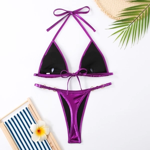 Détail d'un bikini violet métallique avec anneaux dorés sur un fond blanc épuré