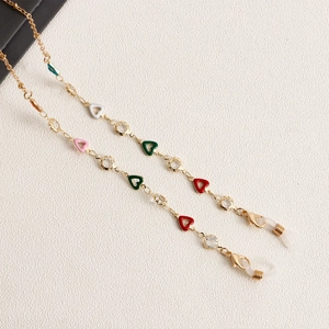 Close-up of golden glasses chain with colorful enamel hearts and sparkling crystals