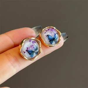 Detailed close-up of amber butterfly earrings with real dried flowers and 18K gold plating