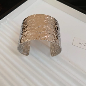 Macro detail of silver wide open cuff bracelet with irregular hammered metal texture