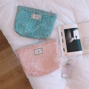 Close-up of daisy lace embroidery and textured fabric on light blue and pink pouches
