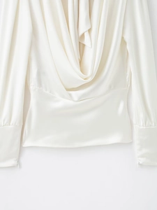 Détail d'un haut blanc en satin à manches longues avec col bénitier et texture soyeuse