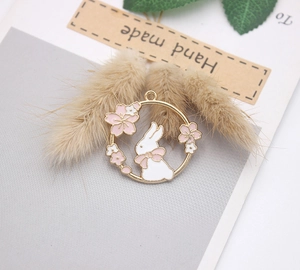 Detail of bunny enamel pendant with pink bow and cherry blossoms on handmade tag