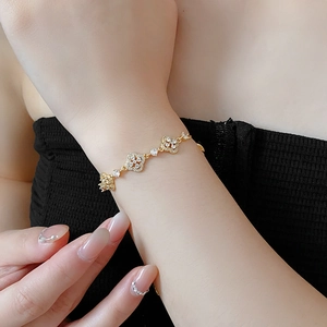 Close-up of gold-plated hollow flower bracelet with clear crystals on female wrist