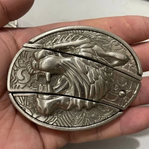 Macro detail of vintage silver belt buckle featuring a 3D leopard head relief and 2002 carving