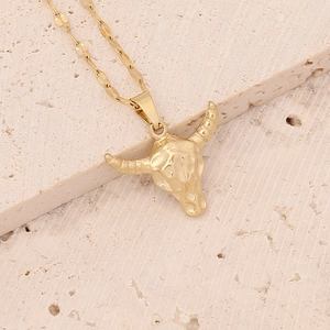 Macro view of golden stainless steel bull head pendant with textured hammered finish