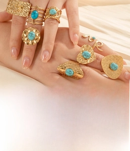 Set of 8 gold titanium steel rings with turquoise inlay on a female hand model