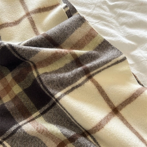 Close-up of soft plaid scarf with cream and brown checkered pattern and fringe texture
