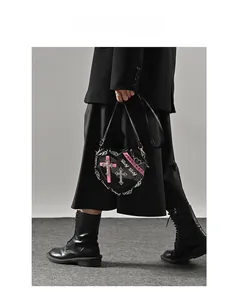 Close-up of heart-shaped gothic bag featuring silver chains and pink cross details