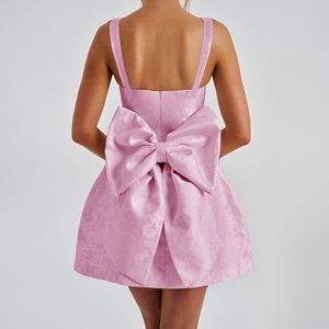 Détail d'une robe rose en jacquard avec un grand nœud au dos et texture du tissu