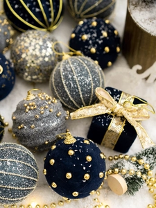 Close-up of gold and navy velvet Christmas ornaments with glitter details on snowy surface