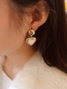 Detail of 18K gold plated heart earrings on model showing fine engraved textures